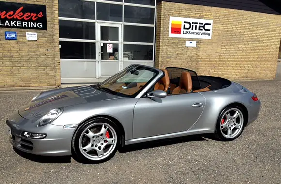 Sølvfarvet Porsche cabriolet foran Denckers Autolakering